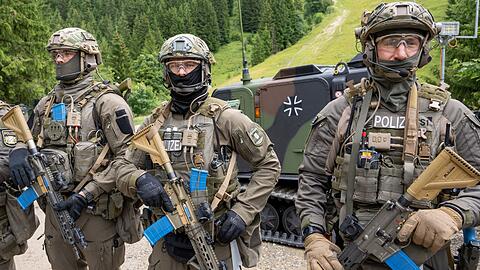 Polizisten des bayerischen SEK stehen vor einem Bundeswehrfahrzeug.