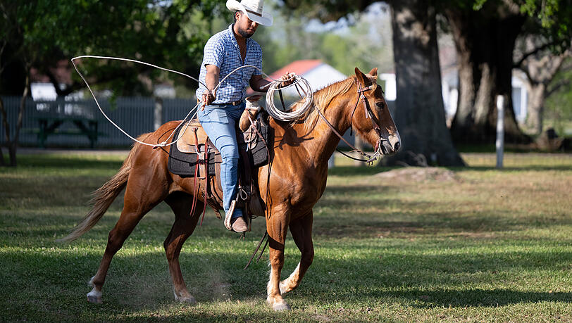 Ein Cowboy reitet bei dem Besuch auf der George Ranch.