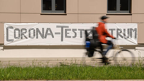 Ein Radfahrer fährt an einem Banner mit der Aufschrift "Corona-Testzentrum" vorbei.