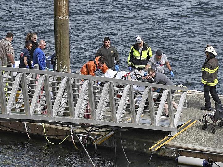 Rettungskräfte transportieren einen verletzten Passagier zu einem Krankenwagen in den Docks des George Inlet vor der Küste von Alaska.
