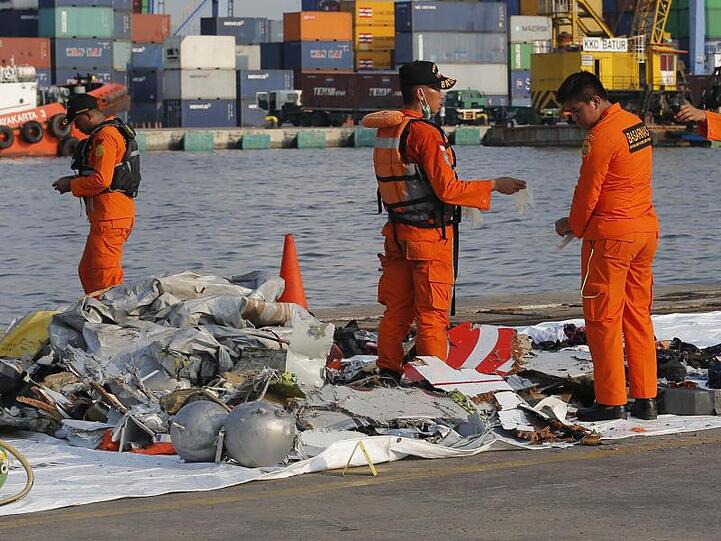 Mitarbeiter der indonesischen Such- und Rettungsbehörde inspizieren Trümmerteile.