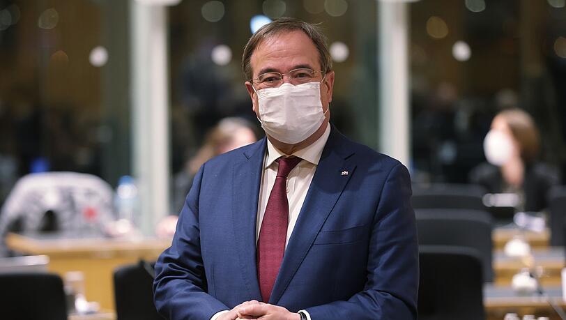 Armin Laschet steht in einem Raum.