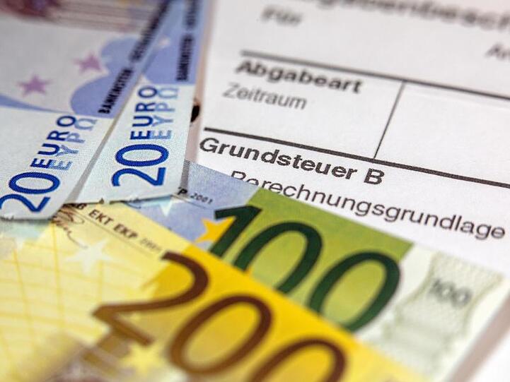 Euro-Geldscheinen liegen auf einem Abgabenbescheid für die Entrichtung der Grundsteuer.