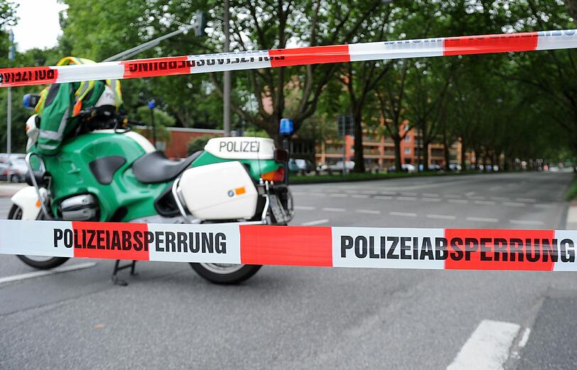 Ein Polizei-Motorrad steht auf einer leeren und gesperrten Hauptverkehrsstraße.