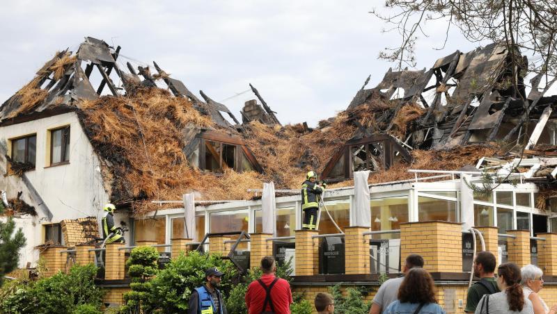 Urlauber und Feuerwehrleute stehen vor dem ausgebrannten Ostseehotel auf der Halbinsel Fischland-Darß-Zingst. Urlauber und Feuerwehrleute stehen vor dem ausgebrannten Ostseehotel auf der Halbinsel Fischland-Darß-Zingst.