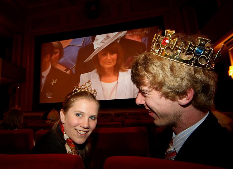 Mit Krone und Krönchen &ndash; aus Pappe: Zwei Royalisten haben es
sich im Kino bequem gemacht und bleiben stundenlang.