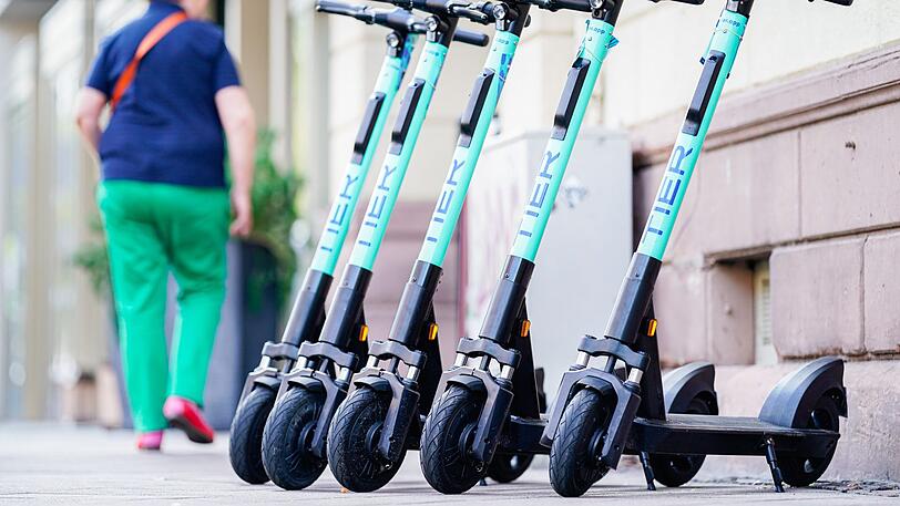 E-Scooter stehen am Rand eines Bürgersteigs.