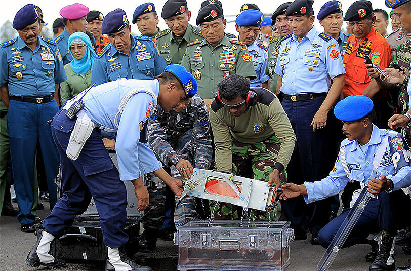 Indonesische Streitkräfte heben die Blackbox der abgestürzten AirAsia-Maschine aus einer Transportbox.