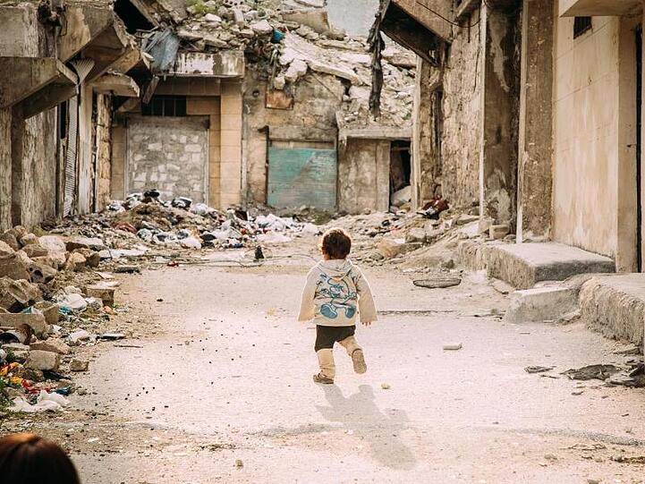 Ein kleiner Junge geht durch eine vom Bürgerkrieg zerstörte Straße in der syrischen Metropole Aleppo.
