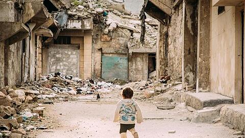 Ein kleiner Junge geht durch eine vom Bürgerkrieg zerstörte Straße in der syrischen Metropole Aleppo.