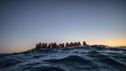 Migranten aus verschiedenen afrikanischen Nationen warten in einem Boot vor der libyschen Küste im Mittelmeer auf Helfer.