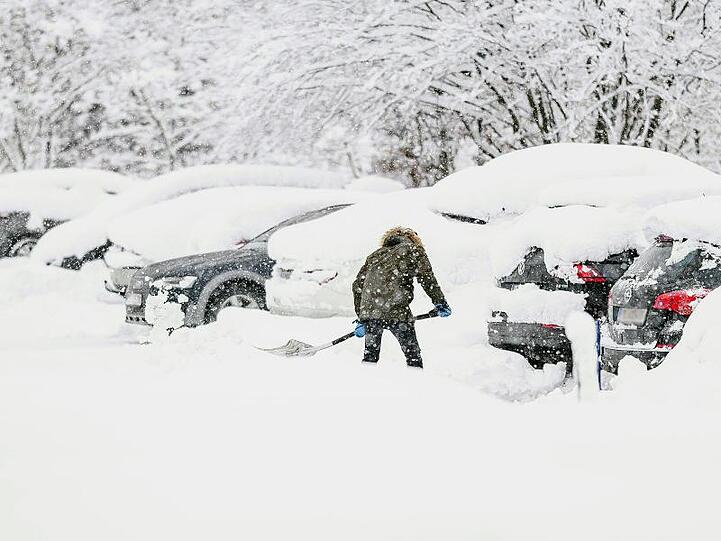 Ein Mann schaufelt sein Auto auf einem Parkplatz aus dem Schnee. Nach Angaben des Deutschen Wetterdienstes ist bis mindestens Mitte nächster Woche vor allem im Alpenraum mit Schnee zu rechnen.