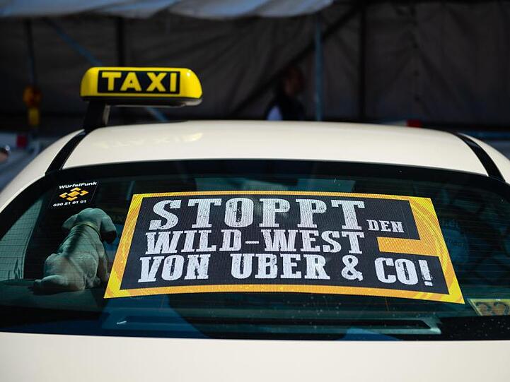 Ein Taxi mit einem Protestschild am Rand einer Demonstration gegen Uber.