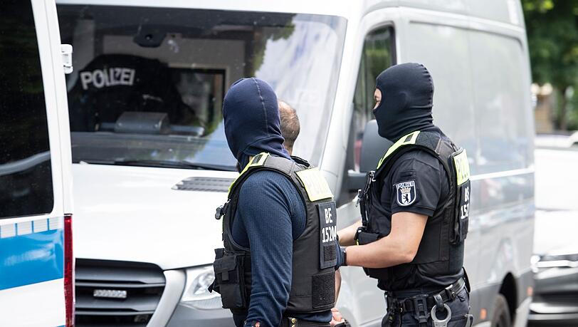 Polizisten führen einen Mann ab. Mit einer  Razzia ist die Polizei in Berlin gegen den organisierten Drogenhandel vorgegangen.