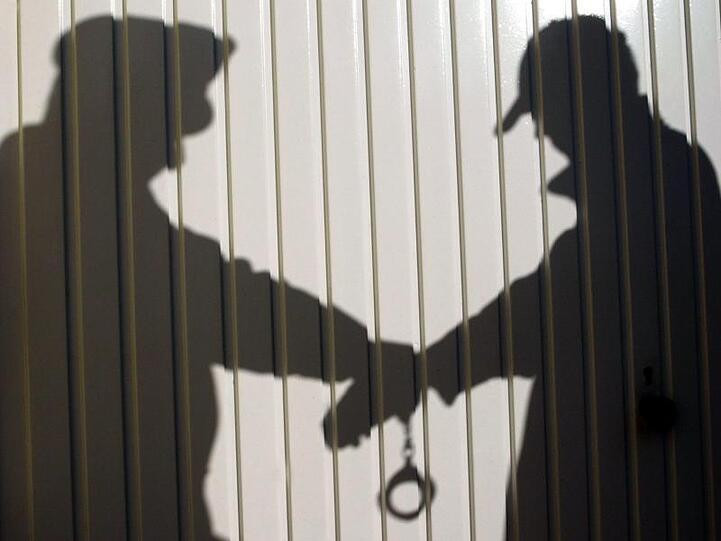 Schattenriss eines Polizisten, der eine Person festnimmt und ihm die Handschellen anlegt. Foto: Marcus Führer/dpa