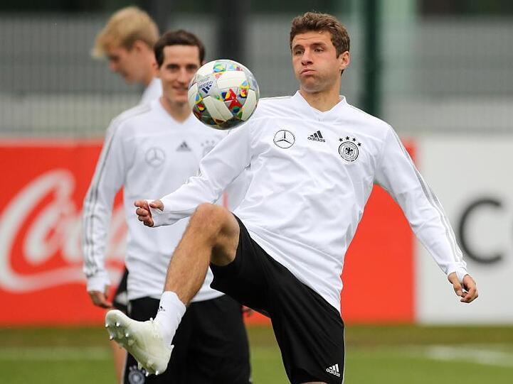 Thomas Müller hält den Ball hoch.