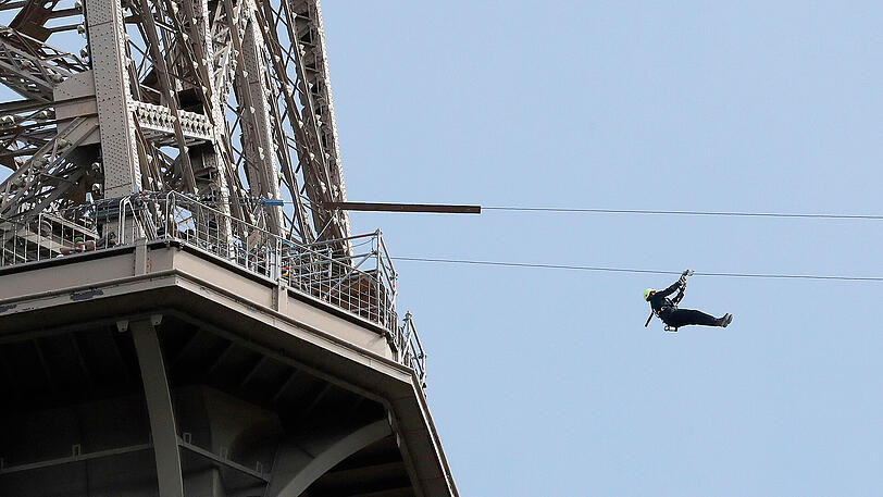 Ein Mann rutscht an einer Zipline-Rutsche vom Eiffelturm in Paris hinunter. Die Rutschpartie startet in etwa 115 Metern Höhe.