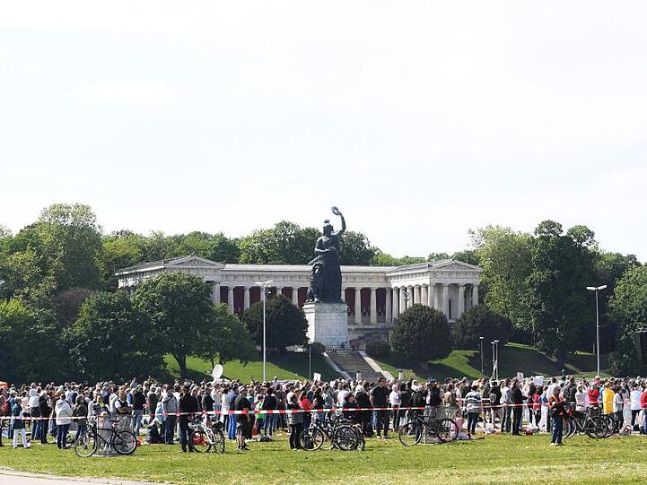 Teilnehmer einer Demonstrationen gegen die Anti-Corona-Maßnahmen der Politik stehen auf der Theresienwiese. Foto: Felix Hörhager/dpa