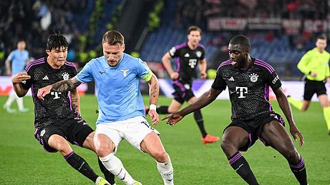 Münchens Minjae Kim (l) und Dayot Upamecano (r) kämpfen mit Roms Ciro Immobile um den Ball.