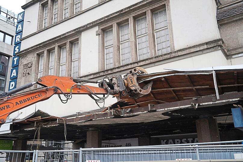 Gegenüber, an der historischen Fassade des Karstadt, hat der Abriss des Vordachs begonnen. Das gibt den Blick frei ins entkernte Erdgeschoss. Wie René Benkos geplanter Shopping-Erlebnistempel wohl bis 2023 aussehen wird?