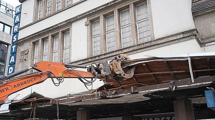 Gegenüber, an der historischen Fassade des Karstadt, hat der Abriss des Vordachs begonnen. Das gibt den Blick frei ins entkernte Erdgeschoss. Wie René Benkos geplanter Shopping-Erlebnistempel wohl bis 2023 aussehen wird?