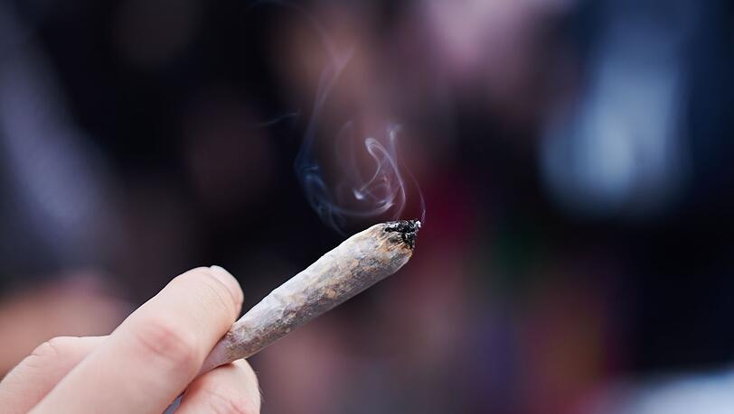 Eine Frau hält einen Joint mit Cannabis in der Hand.