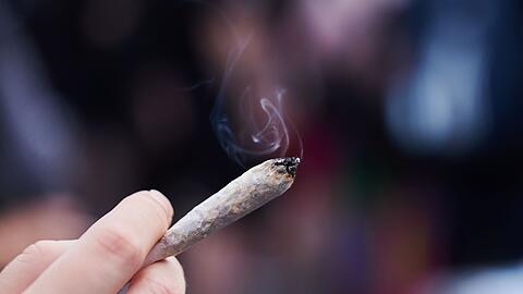 Eine Frau hält einen Joint mit Cannabis in der Hand.
