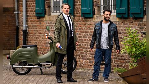 "Friesland: Artenvielfalt": Wolfgang Habedank (Holger Stockhaus, l.) und Yunus (Yunus Cumartpay) stehen irritiert vor dem Zollamt, weil ein Zollbeamter vor ihnen wegzurennen scheint.