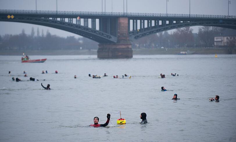 Die Teilnehmer sprangen von einem Feuerwehrboot aus in den Rhein, um mehrere hundert Meter flussabwaerts zu schwimmen.