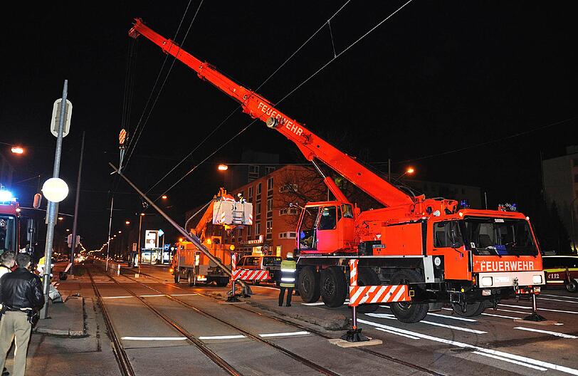 Mithilfe eines Krans versuchen sie den Pfosten aus der Oberleitung zu entfernen.