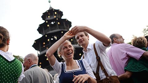 Ein Paar beim Kocherlball am Chinesischen Turm. Viele Besucher sind jung.