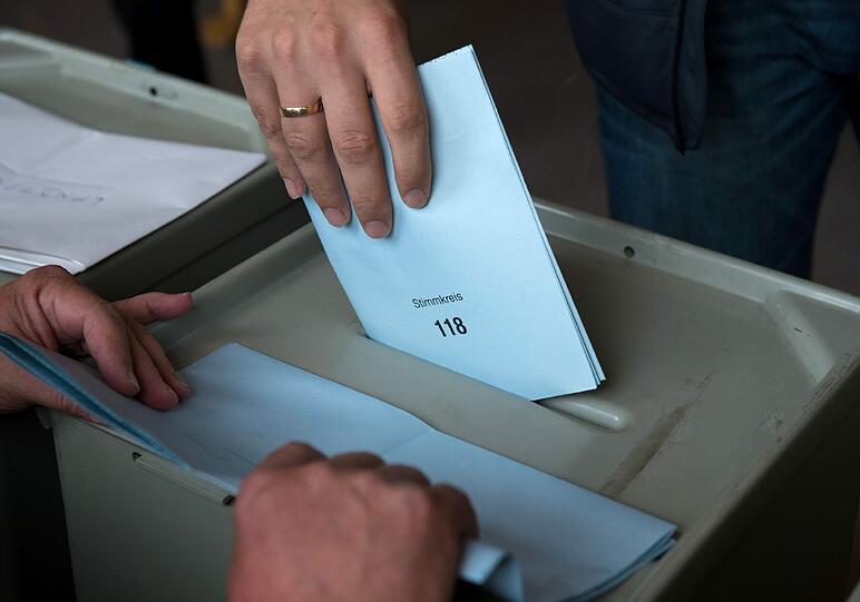 Ein Mann wirft in Ingolstadt (Bayern) seinen Stimmzettel zur Landtagswahl in die Wahlurne.