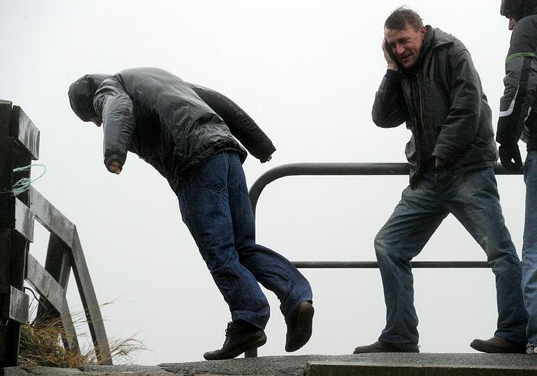 Passanten kämpfen in Dagebüll (Schleswig-Holstein) gegen den Sturm
