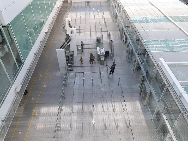 Sicherheitspersonal wartet an der Gepäckkontrolle am Flughafen München auf die wenigen Passagiere. Foto: Peter Kneffel/dpa