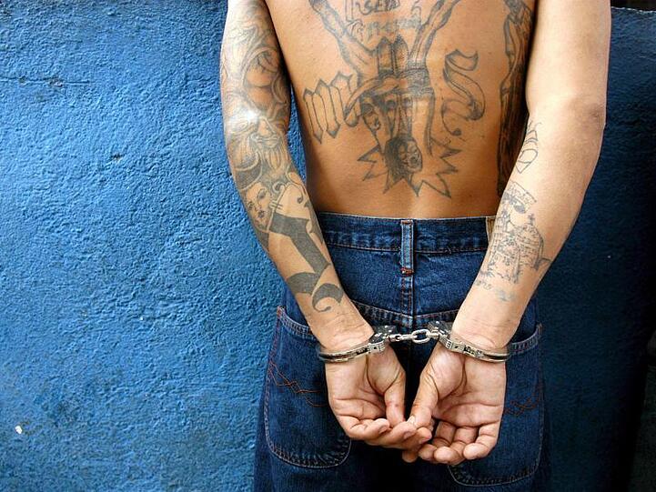 Auf dem Archivbild steht ein Mitglied der Verbrecherbande "Mara Salvatrucha" (M-13) nach seiner Festnahme mit Handschellen an einer Wand.