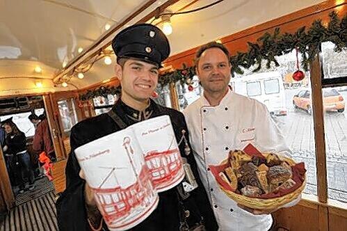 Schaffner Tobias Schneider und Konditor Thomas Neuer (rechts) servieren Glühwein und Lebkuchen bei den Fahrten mit der historischen Straßenbahn rund um die Altstadt.