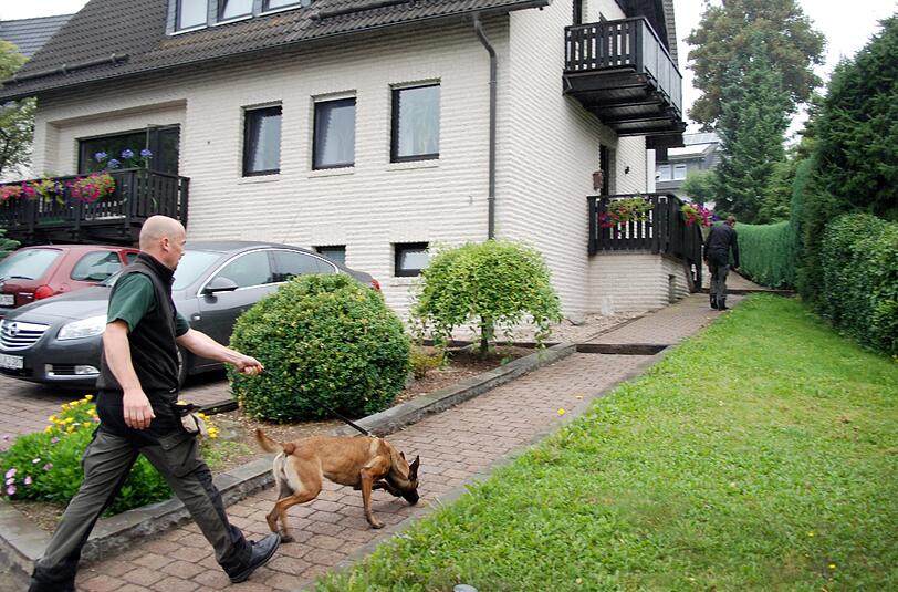 Ein Hundeführer geht im sauerländischen Eslohe in das Haus eines Ehepaares, in dem die Polizei zwei Babyleichen gefunden hat.