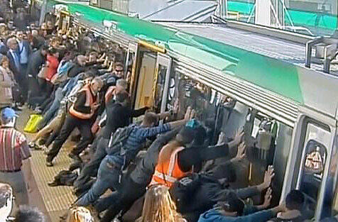 Hier war pure Muskelkraft gefragt: Fahrgäste versuchen einen Zug von den Schienen zu heben um einen festgeklemmten Mann zu befreien.