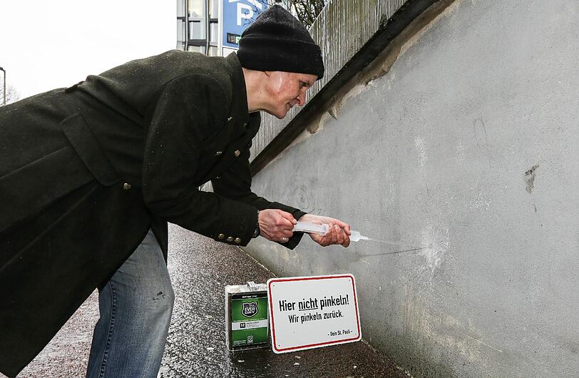 Quartiermanagerin der Reeperbahn, Julia Staron, demonstriert wie der Anti-Pissel-Lack funktioniert.