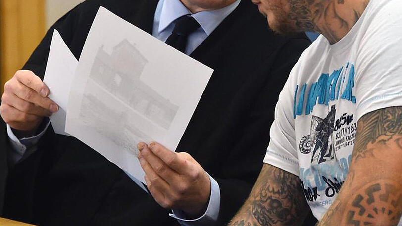 Der Angeklagte und dessen Anwalt betrachten Fotos eines Konzentrationslagers.