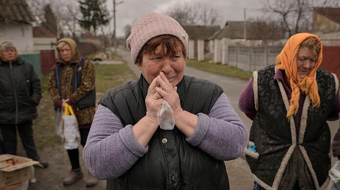 Eine weinende Frau in Motyschyn wartet zusammen mit anderen Dorfbewohnern auf die Verteilung von Lebensmitteln, das bis vor kurzem unter der Kontrolle des russischen Militärs stand.