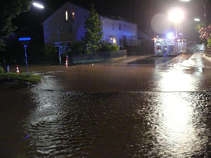 Ein Feuerwehrauto steht an einer überfluteten Straßenkreuzung. Unwetterartige Regenfälle haben in der Nacht zum Sonntag für Überschwemmungen in Teilen von Landsberg am Lech gesorgt.