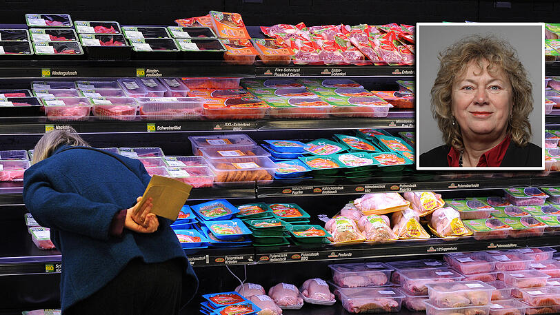 Eine Frau überlegt, welches Fleisch sie im Supermarkt kaufen soll.