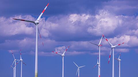 Windkraftanlagen hinter einem blühenden Rapsfeld in einem Windpark in Mecklenburg-Vorpommern.