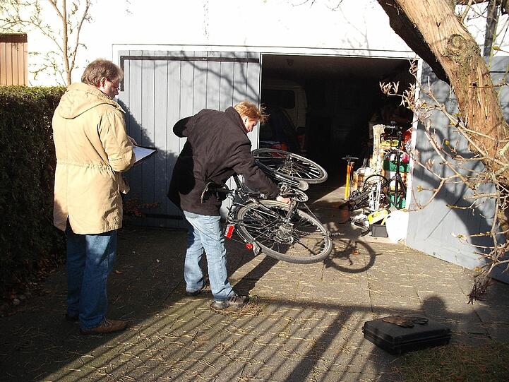 Polizisten sichern in einer Garage ein verdächtiges Fahrrad.