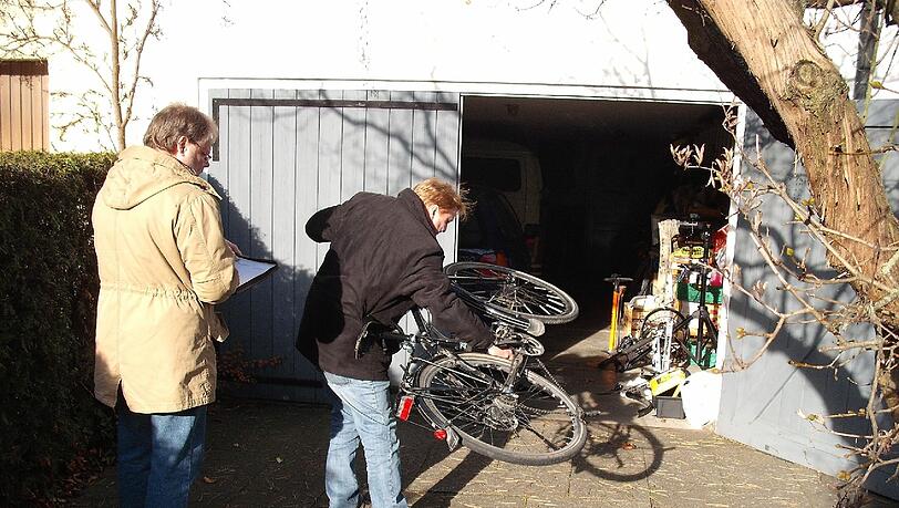 Polizisten sichern in einer Garage ein verdächtiges Fahrrad. Polizisten sichern in einer Garage ein verdächtiges Fahrrad.