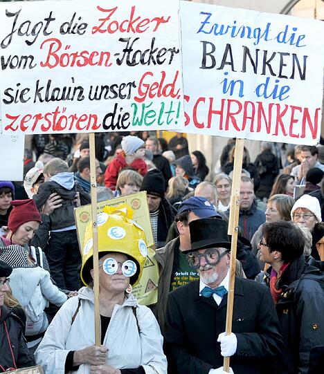 Demonstranten stehen mit Plakaten am Stachus in München (Vorbild der Demonstrationen ist die amerikanische Protestbewegung «Occupy Wall Street» («Besetzt die Wall Street»), die sich gegen das Finanzsystem und große Teile der Bankenwelt wendet.