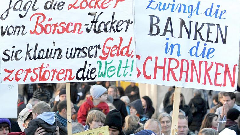 Demonstranten stehen mit Plakaten am Stachus in München (Vorbild der Demonstrationen ist die amerikanische Protestbewegung «Occupy Wall Street» («Besetzt die Wall Street»), die sich gegen das Finanzsystem und große Teile der Bankenwelt wendet. Demonstranten stehen mit Plakaten am Stachus in München (Vorbild der Demonstrationen ist die amerikanische Protestbewegung «Occupy Wall Street» («Besetzt die Wall Street»), die sich gegen das Finanzsystem und große Teile der Bankenwelt wendet.