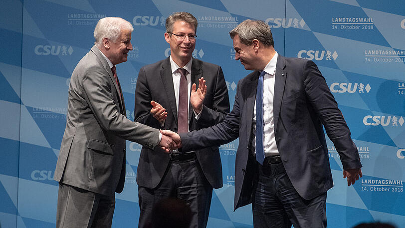 Seehofer (l) und Söder reichen sich die Hand, Generalsekretär Markus Blume applaudiert.