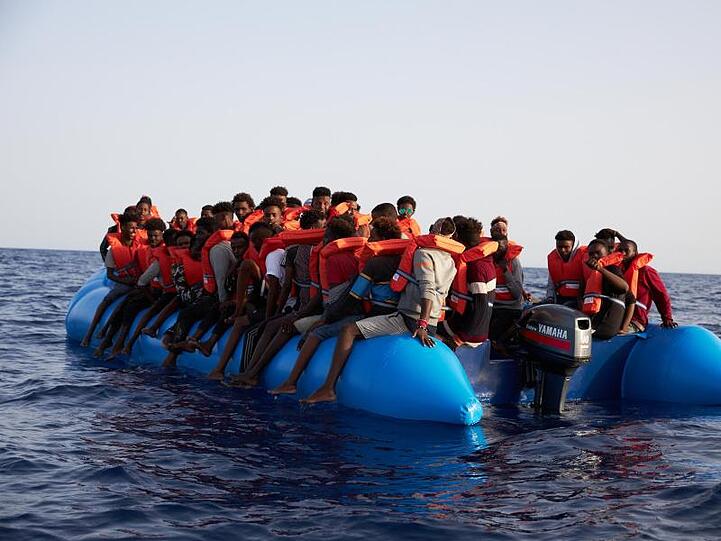Flüchtlinge sitzen vor der Küste von Libyen in einem Schlauchboot, bevor sie vom Hilfsschiff "Alan Kurdi" gerettet werden.